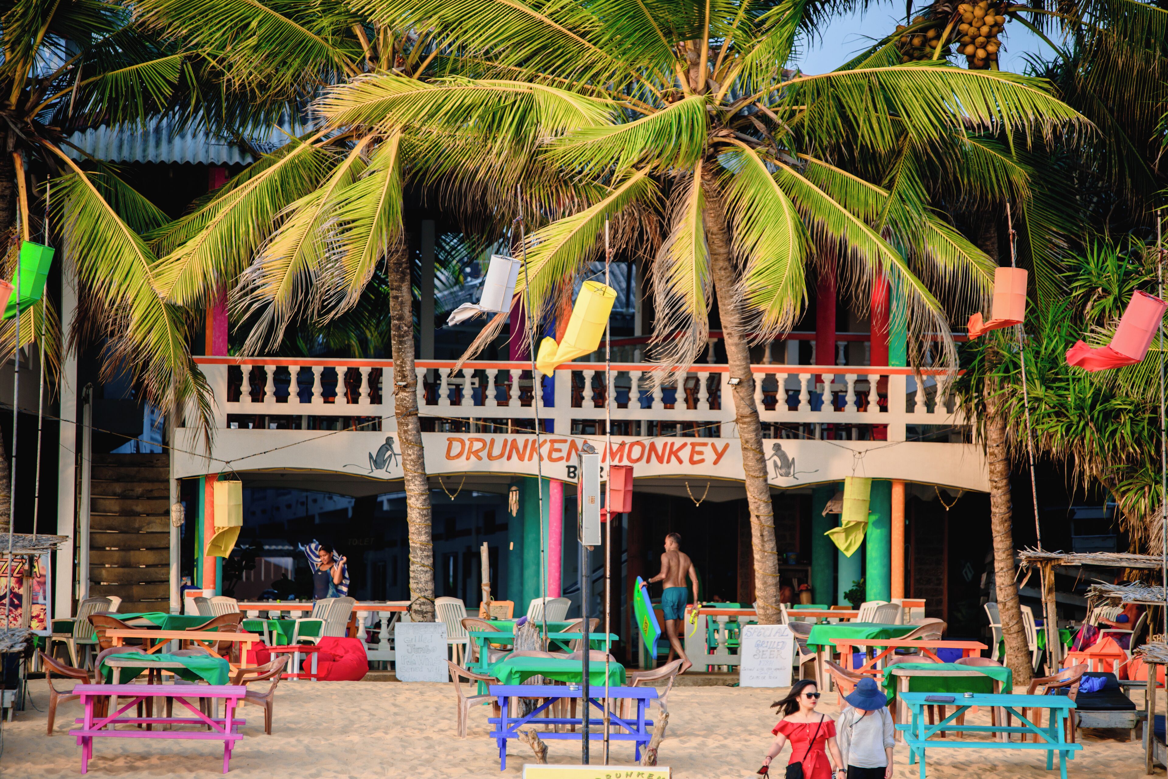 Un bar en la playa llamado 'Drunken Monkey' con terraza y palmeras.