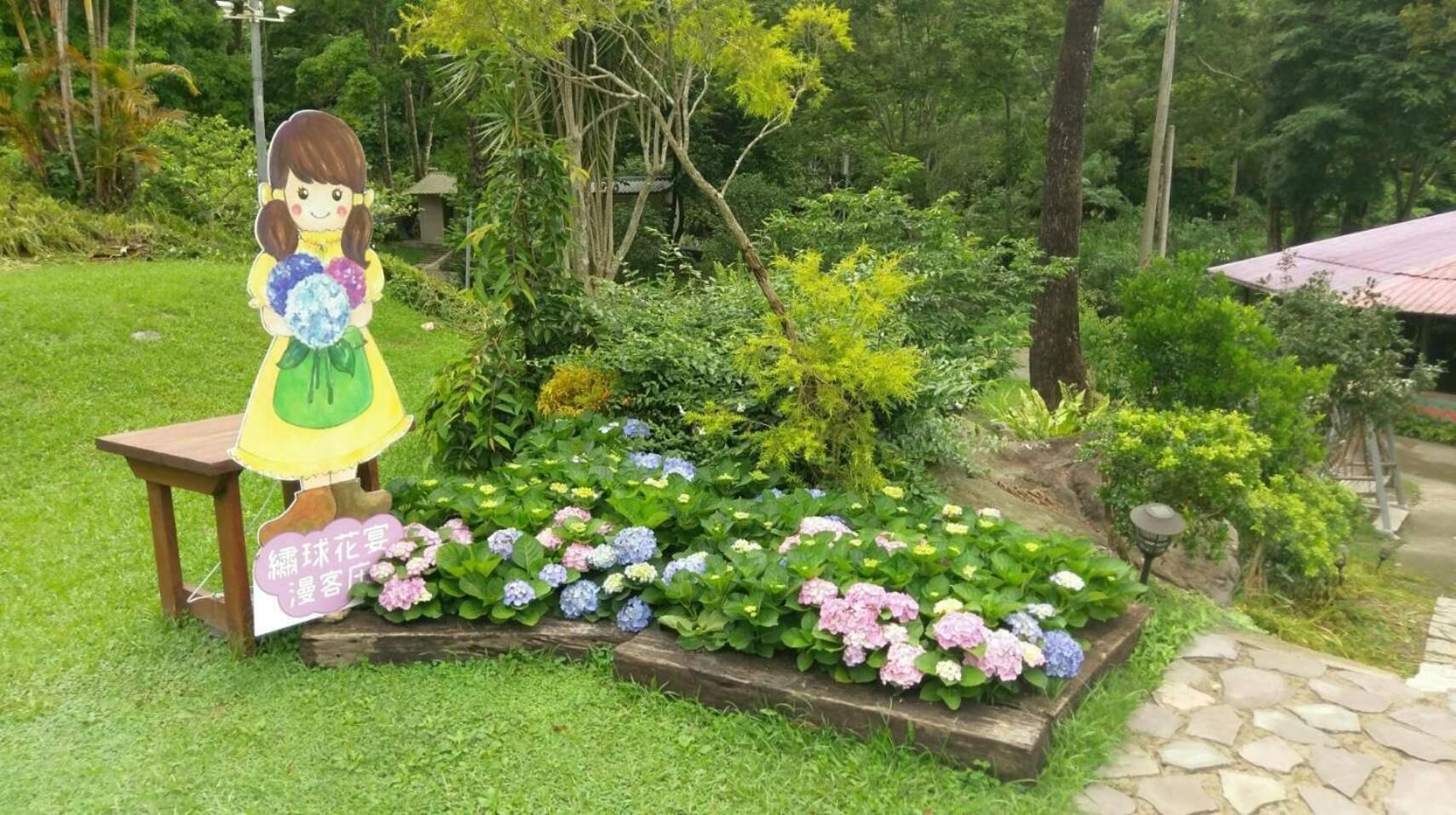 A garden with a wooden bench and a cutout of a girl holding flowers.