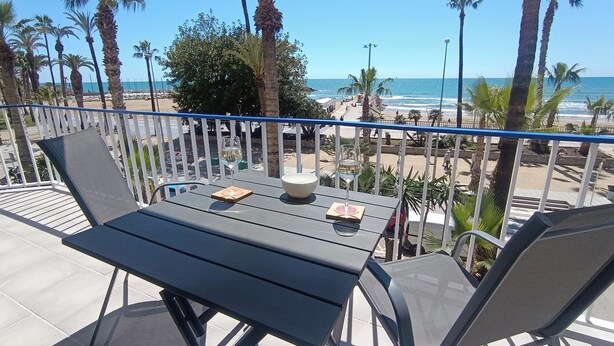 Un balcone con tavolo e sedie, vista sulla spiaggia e sull'oceano.
