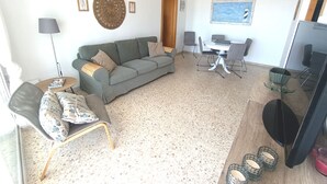 Un soggiorno con divano, poltrone, tavolo da pranzo, televisore e parete decorata con un quadro.