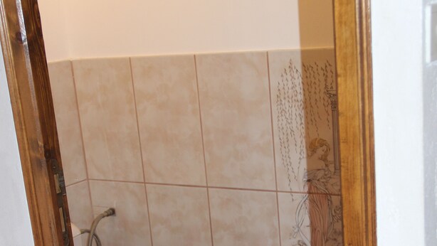 Une salle de bain avec des toilettes en bois, des murs carrelés et un espace douche.