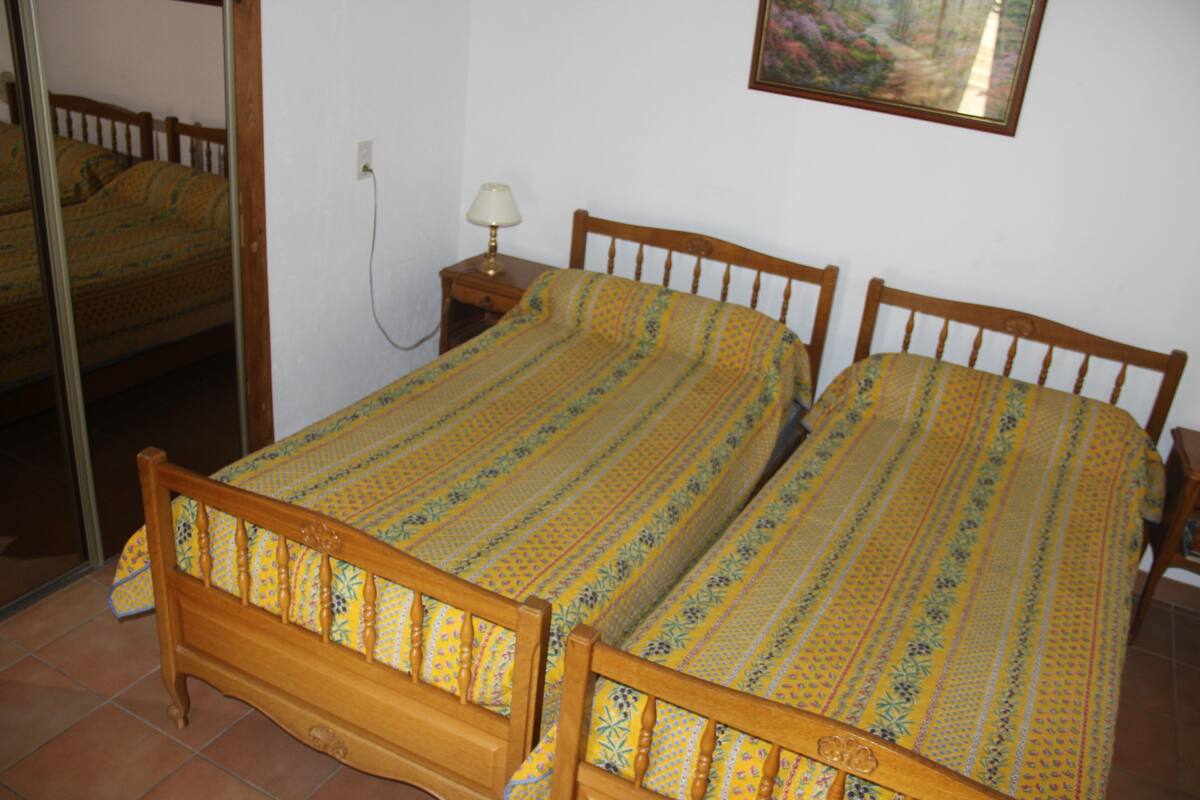 Un lit double avec un cadre en bois et une couvre-lit à motifs, une table de chevet avec une lampe et un miroir au mur.