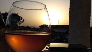A glass of wine on a table with a sunset view.