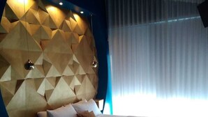 A modern bedroom with a geometric-patterned headboard, a large bed, and a view of the outdoors through sheer curtains. - Le Mammole (San Miniato)