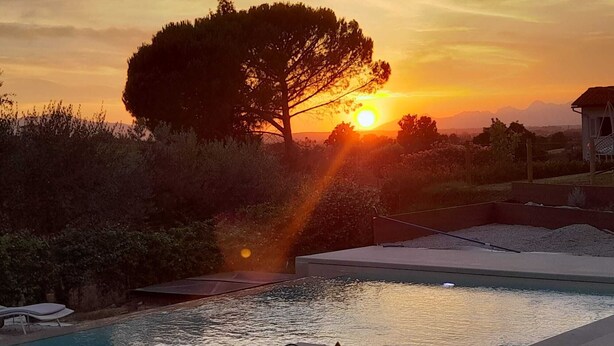 A pool area with a sunset view, surrounded by trees and a distant mountain range. - Le Mammole (San Miniato)