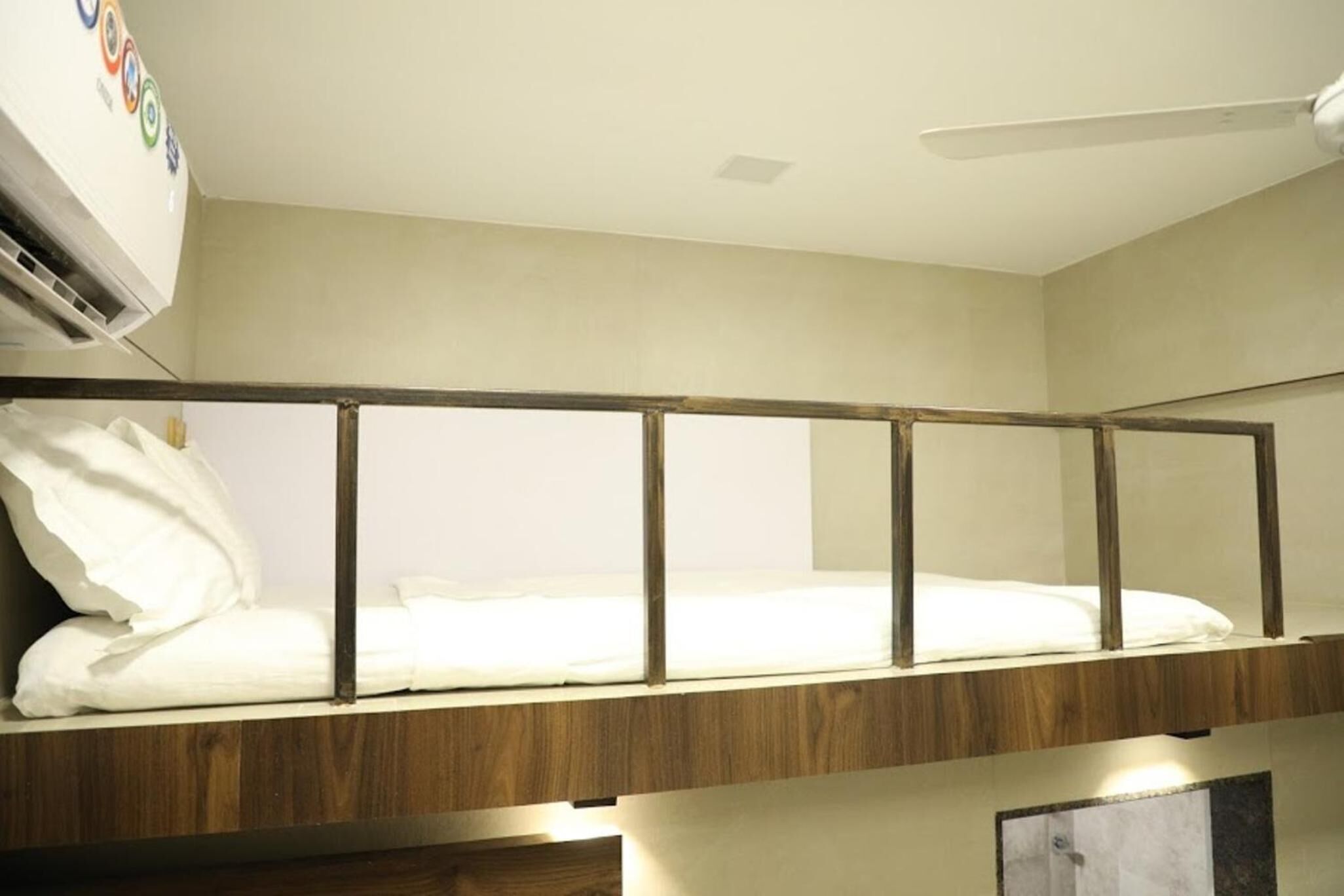 A bunk bed with a wooden frame, white bedding, and a ceiling fan.