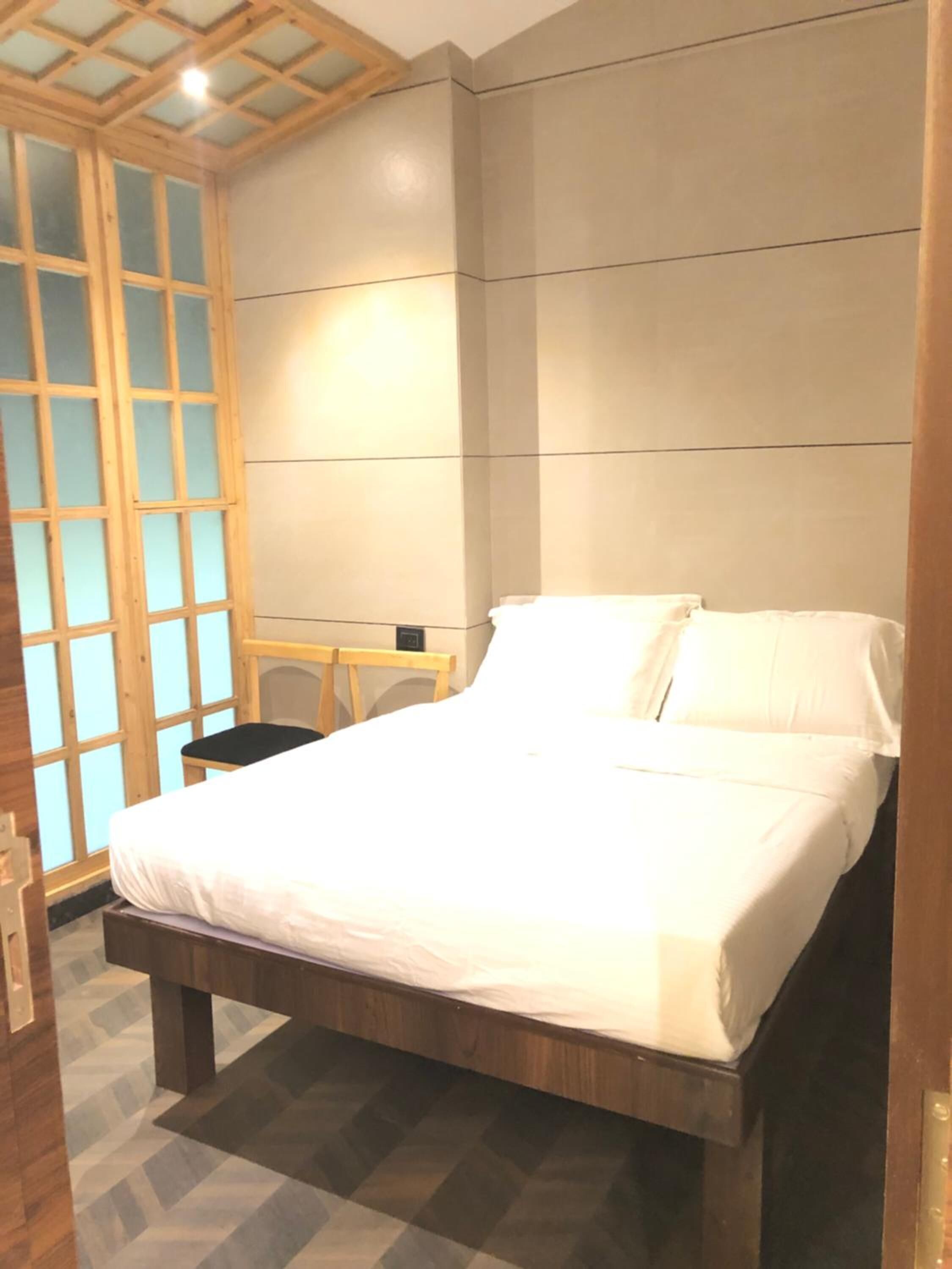 A bedroom with a wooden bed frame, a desk, and a chair.
