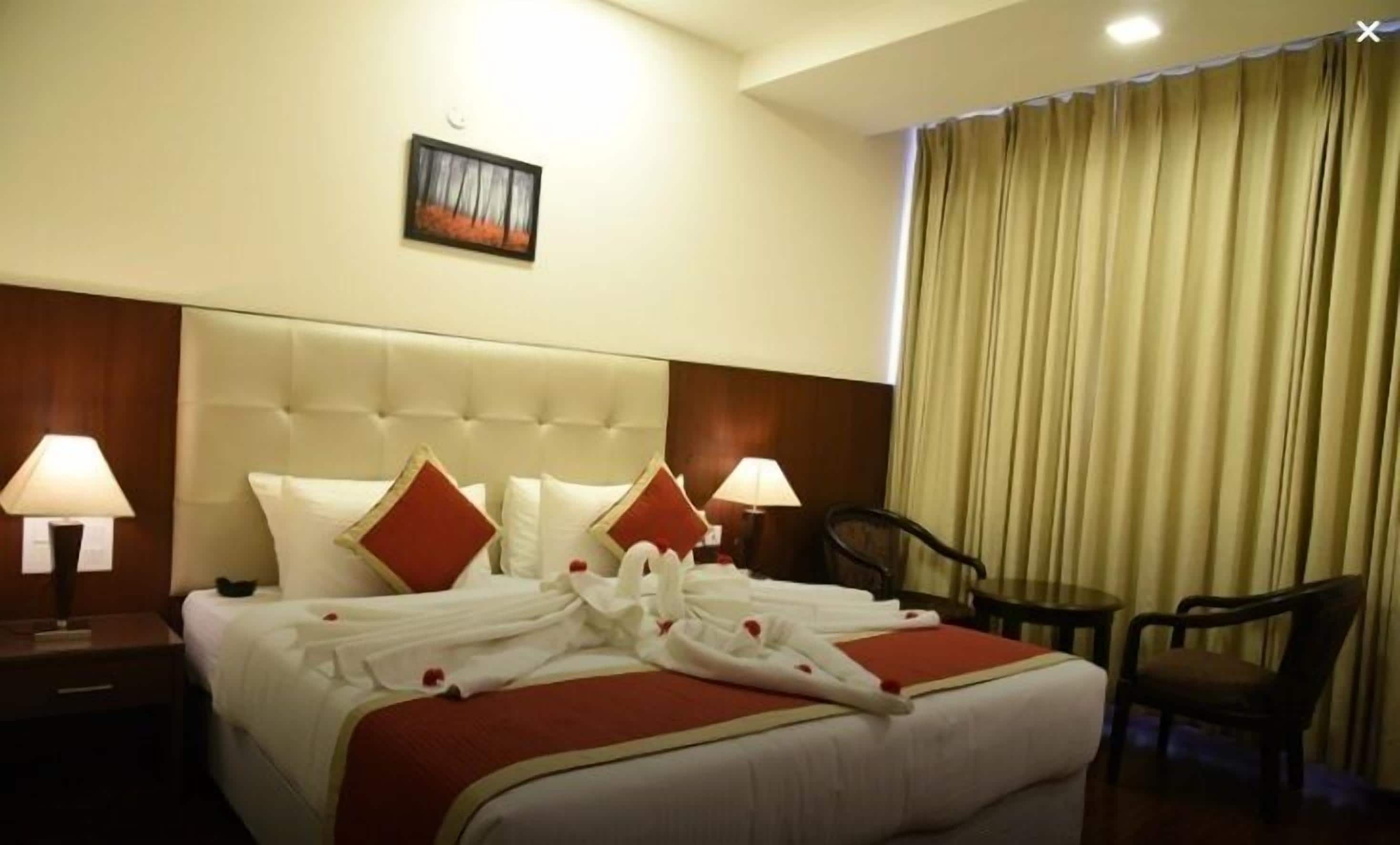 A hotel room with a large bed, two bedside tables with lamps, a chair, and a window with curtains.