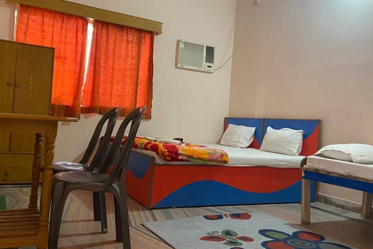 Un dormitorio con cama, una silla, un armario y un equipo de aire acondicionado.