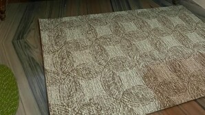 A single bed with a green bedspread, white pillows, and a wooden headboard. A patterned rug is in front of the bed. - Hotel Shanti (Gaya)