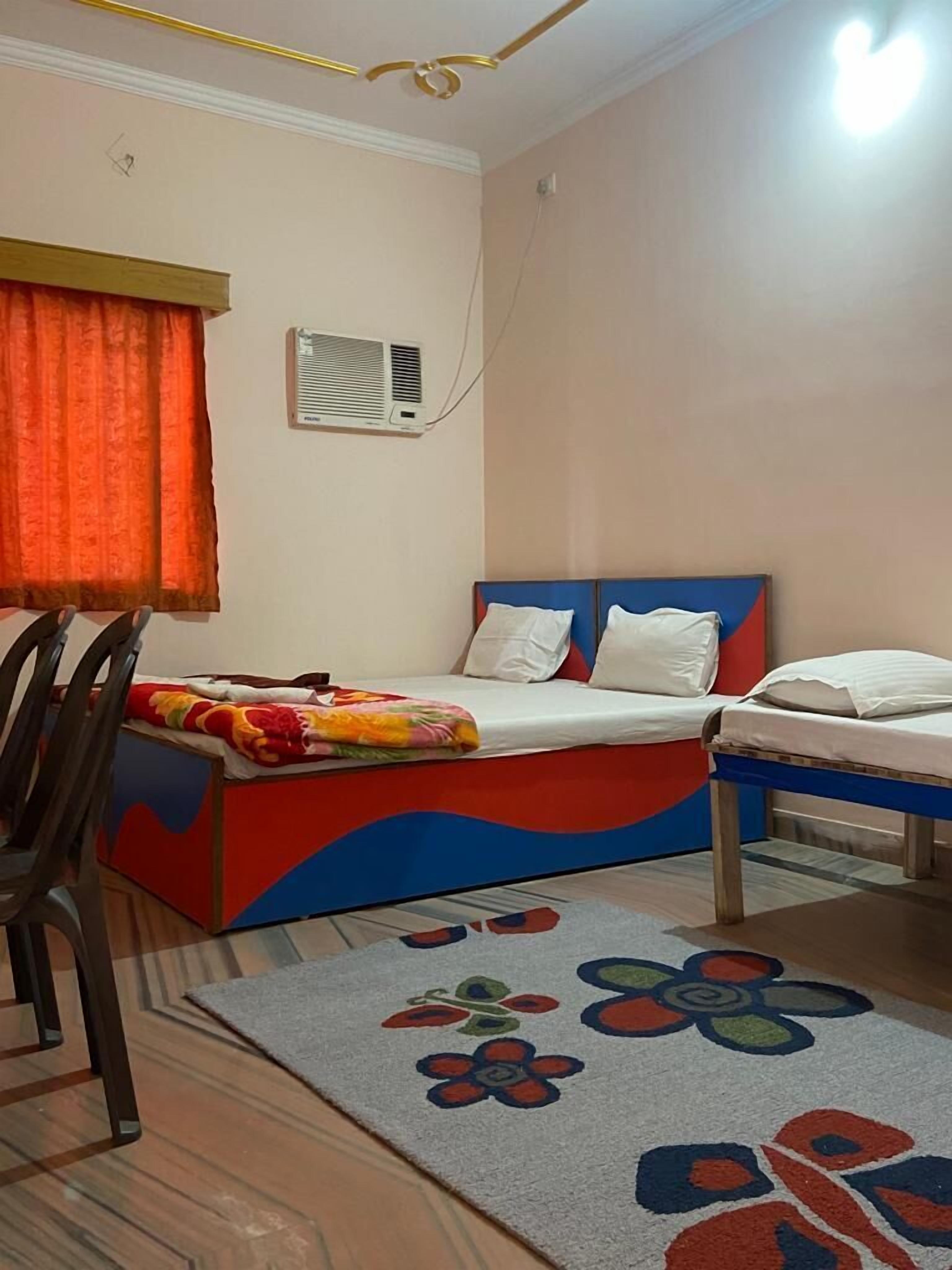Quarto com cama, uma cadeira, mesa de cabeceira e tapete estampado.