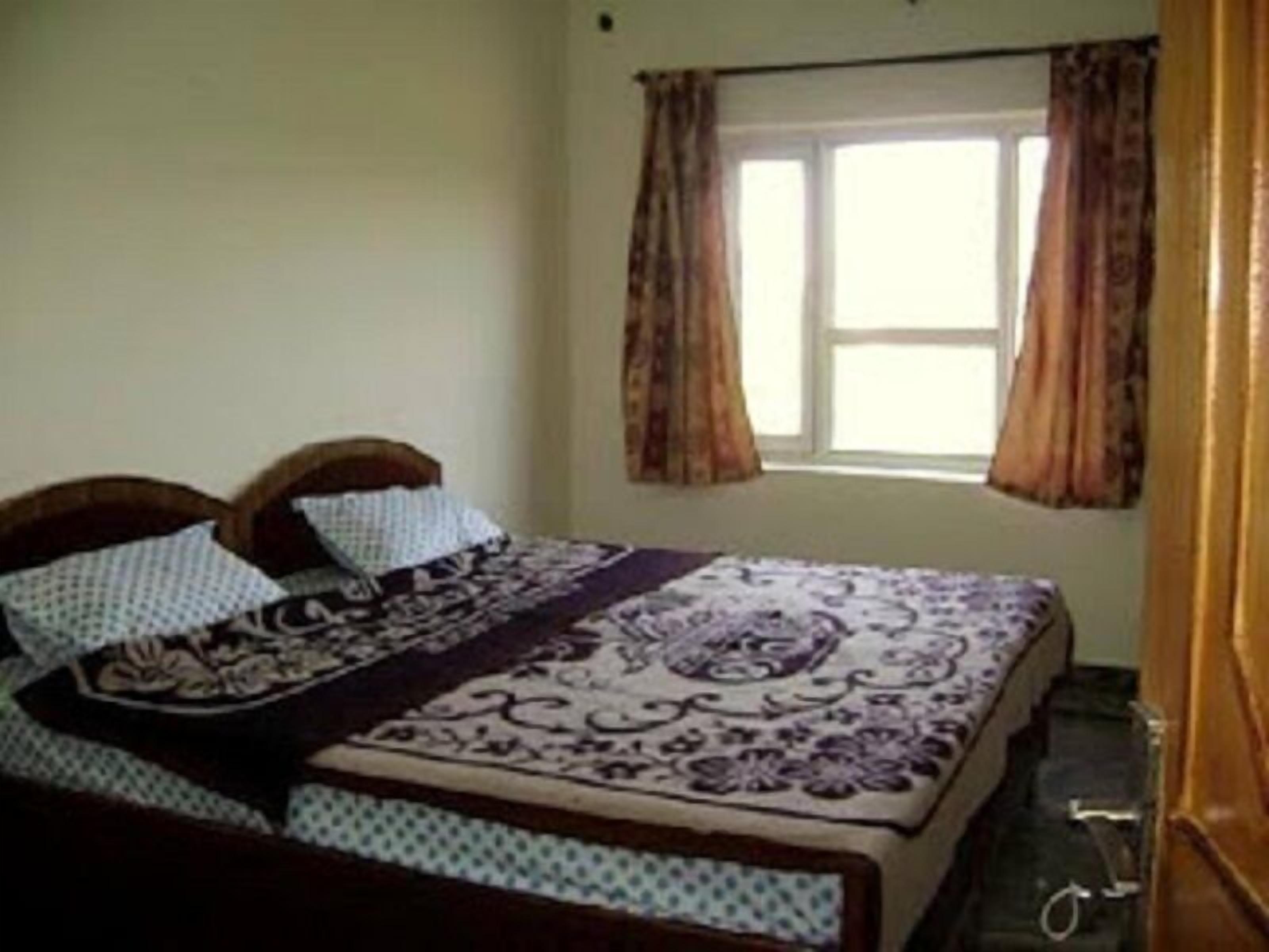 A bedroom with a bed, curtains, and a window.