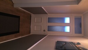 A room with a wooden floor, a white door with frosted glass panels, and a framed picture on the wall.