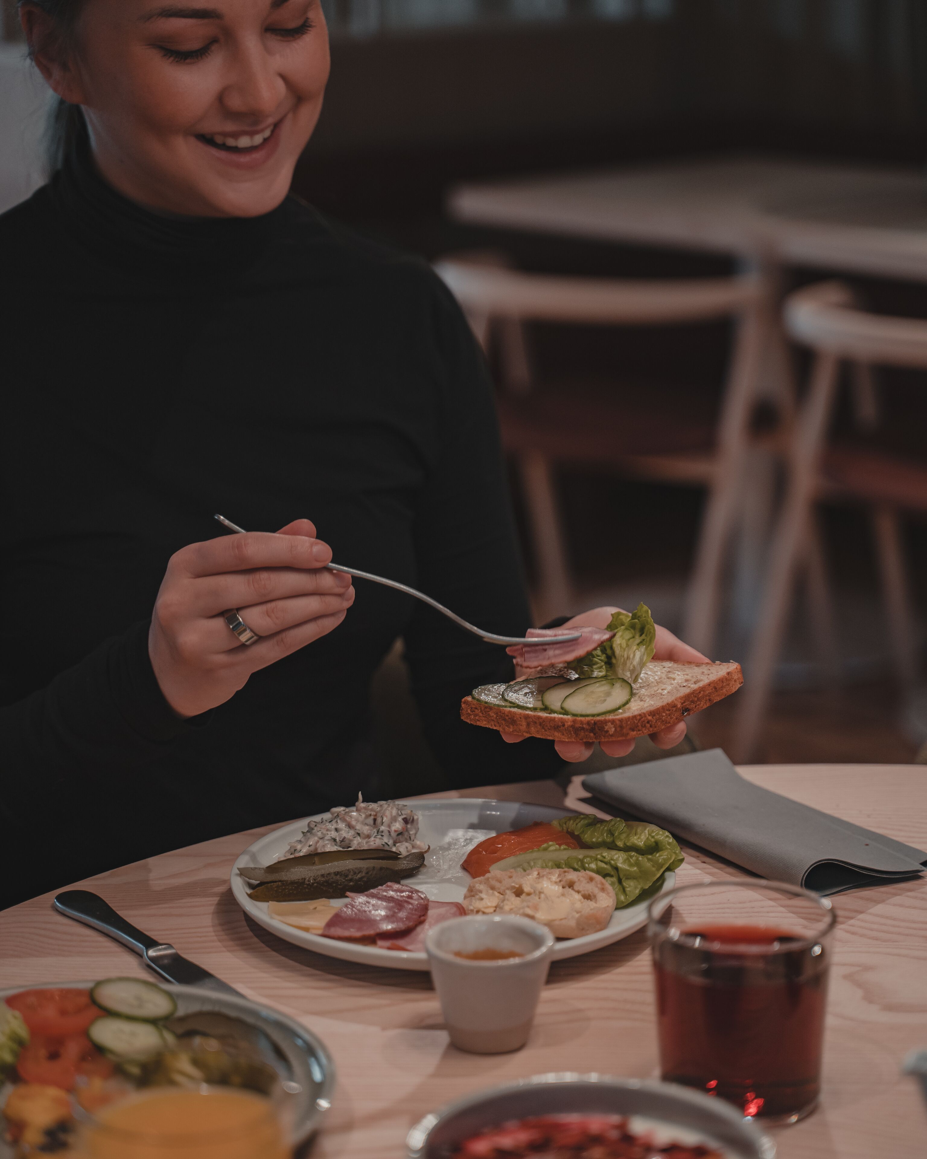 A person sitting at a table with a plate of food, a glass of drink, and a knife and fork.