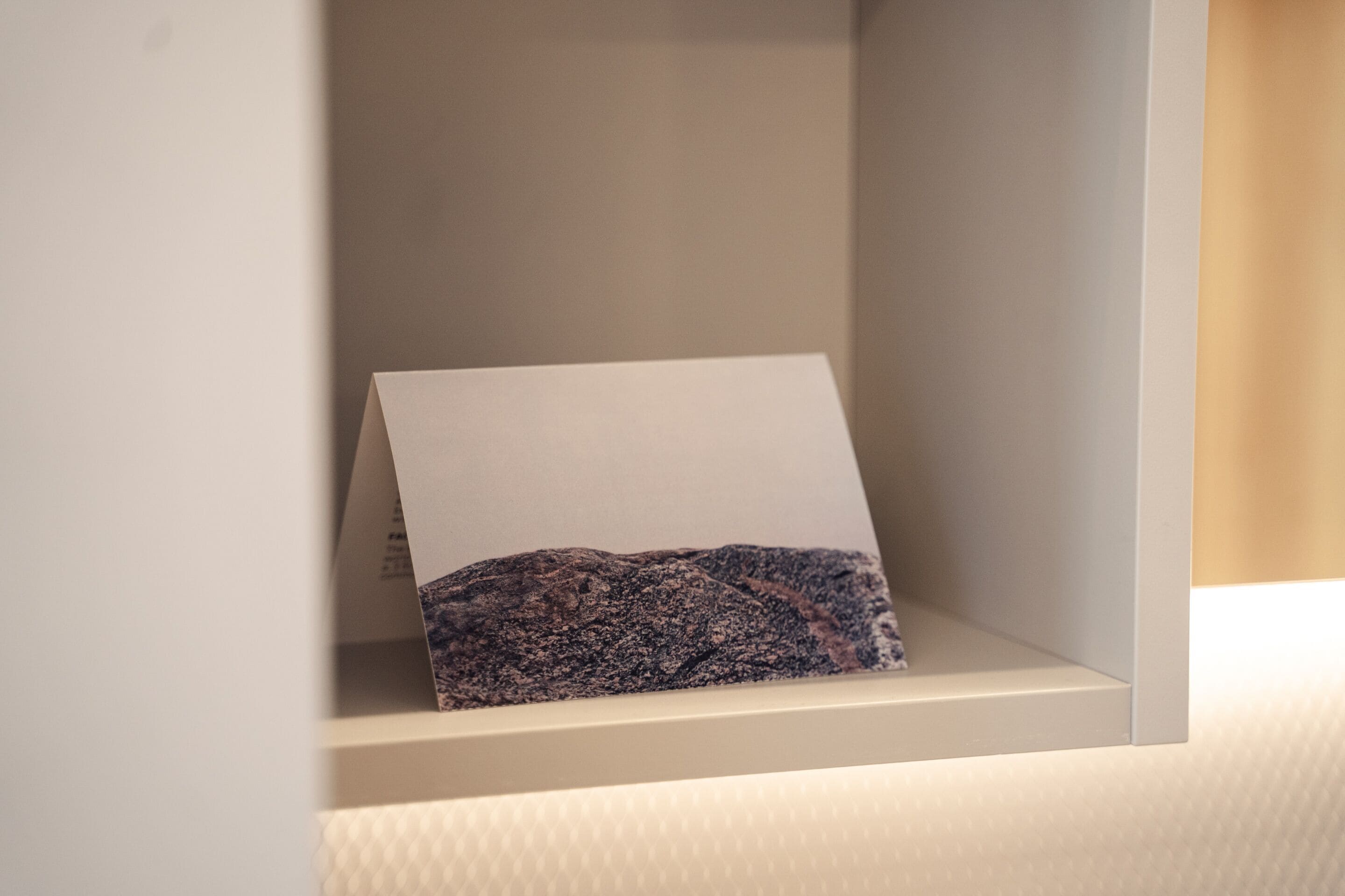 A framed photograph of a rocky landscape on a white shelf.