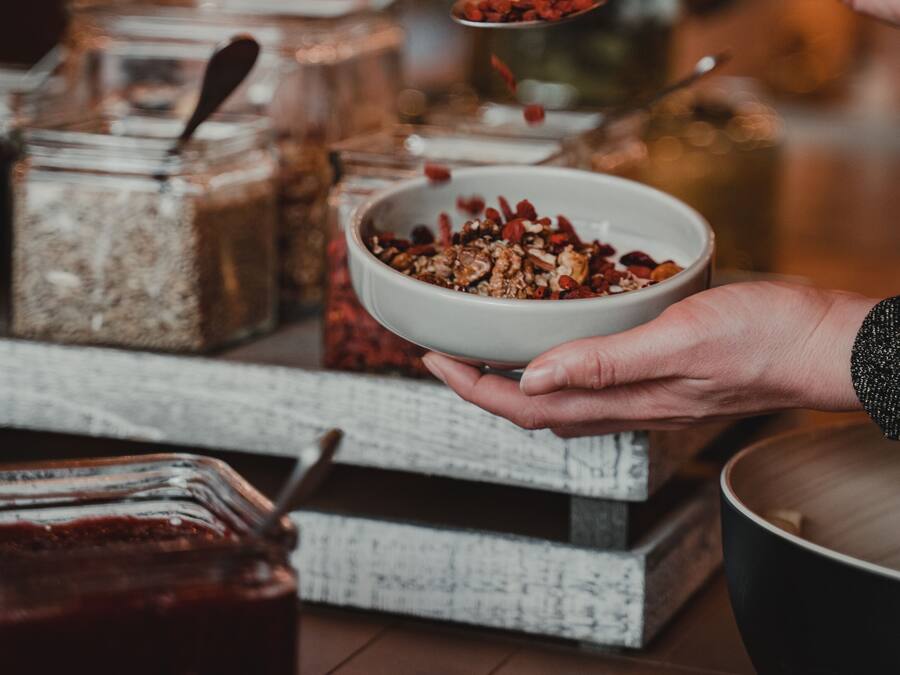 A person holding a bowl of granola with a spoon.