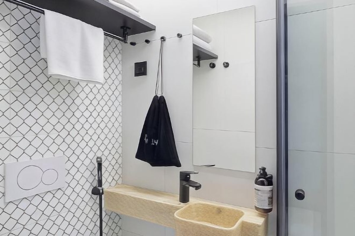 A bathroom with a shower, a sink with a towel rack, and a mirror.