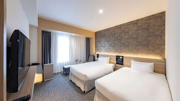 Habitación de hotel con dos camas, televisión, escritorio y una silla.