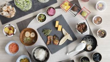 A variety of dishes and condiments arranged on a table, including a bowl of rice, a plate of fish, and several small bowls containing different sauces and vegetables.