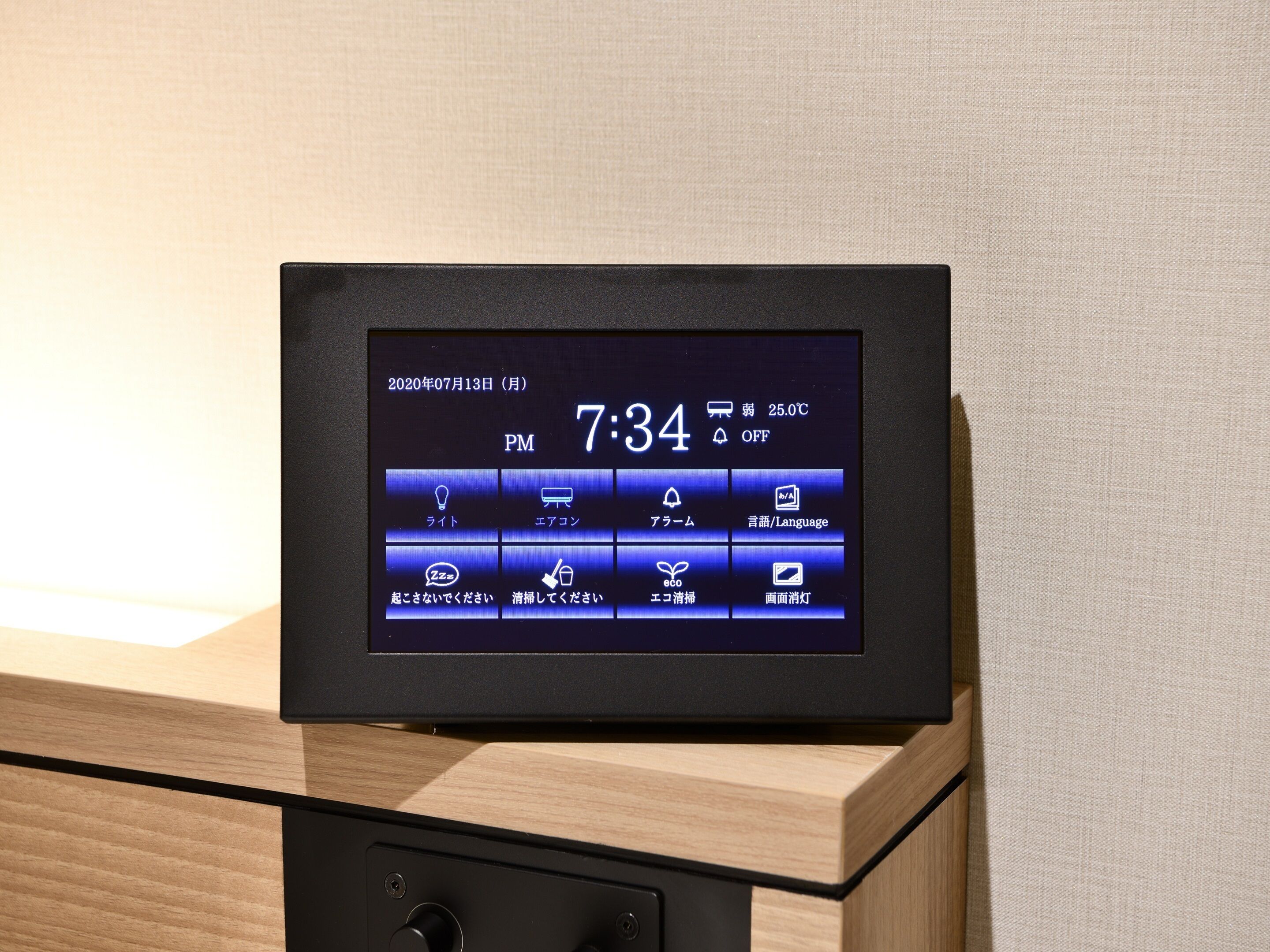A digital display on a wooden dresser with a date and time, temperature, and various icons indicating room features.