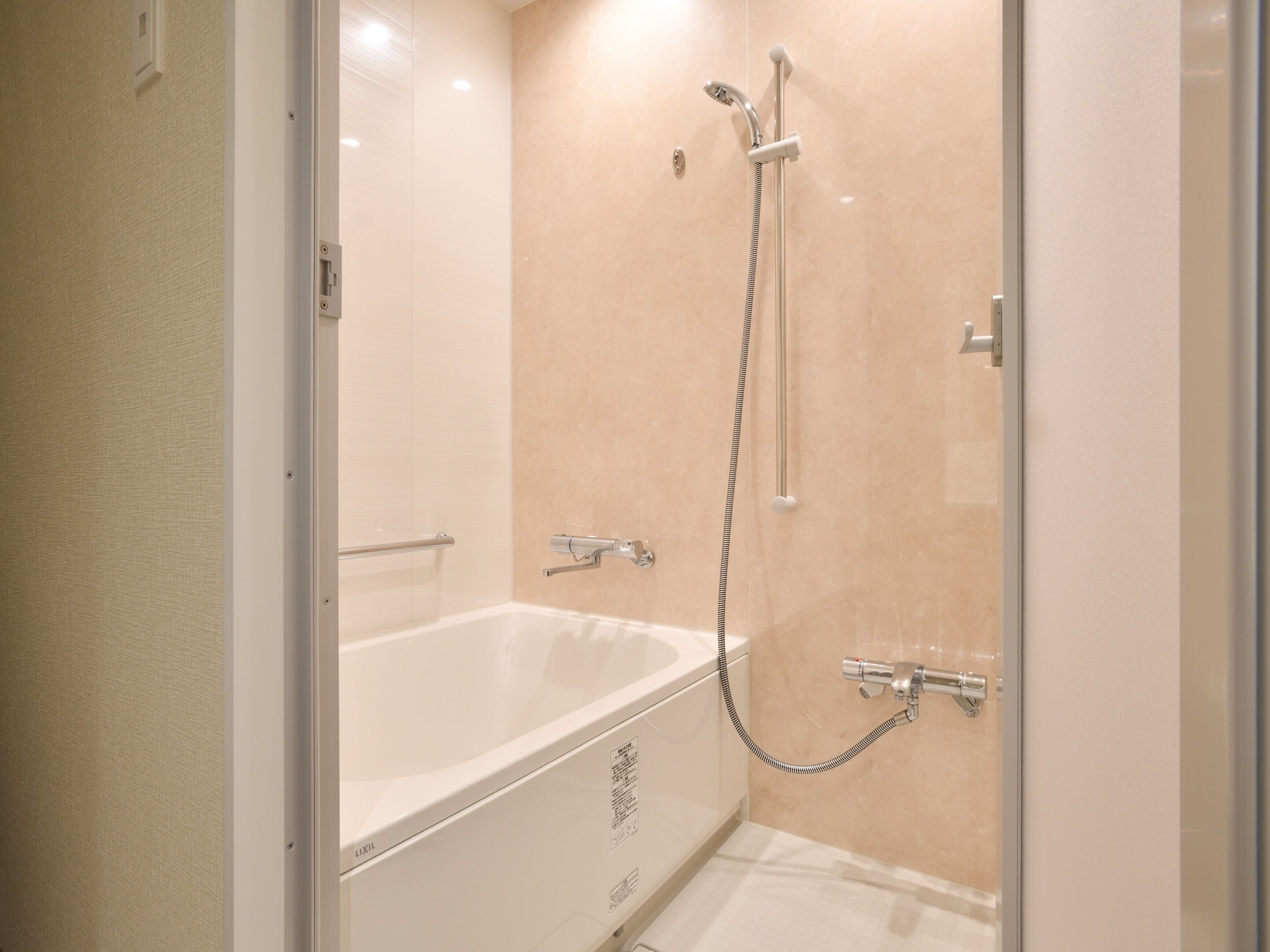 A modern bathroom with a glass-enclosed shower, a white bathtub, and a handheld showerhead.