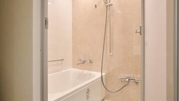 A modern bathroom with a glass-enclosed shower, a white bathtub, and a handheld showerhead.