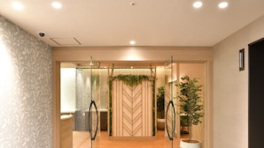 Un intérieur moderne avec un plancher en bois, une porte d’entrée en verre et un mur orné d’un motif en chevrons.