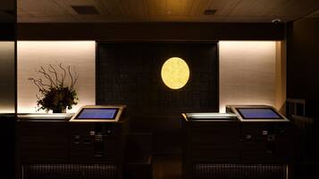 A reception area with two digital kiosks, a large illuminated circular light, and a wall-mounted screen.