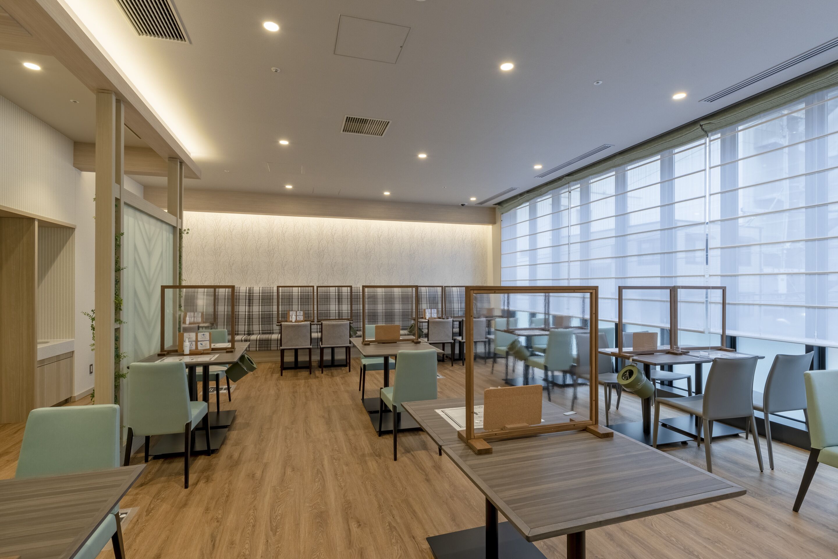 A modern office space with multiple workstations, ergonomic chairs, and large windows providing natural light.