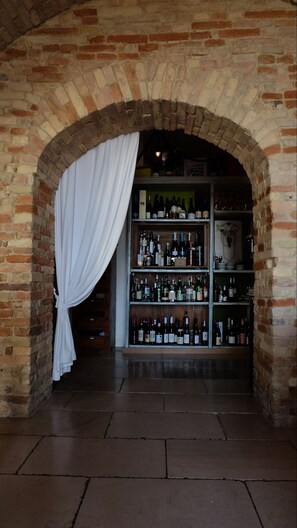 Una pared de ladrillo arqueada con un botellero lleno de botellas.
