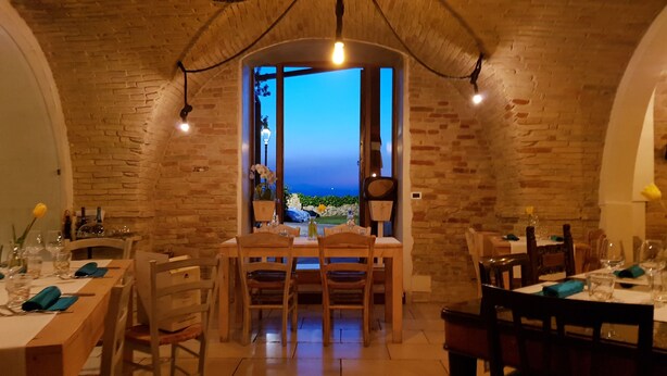 A dining area with brick walls, a table set for four, and a view of the sea through a window. - BR1 Cibo & Benessere (Montesilvano)