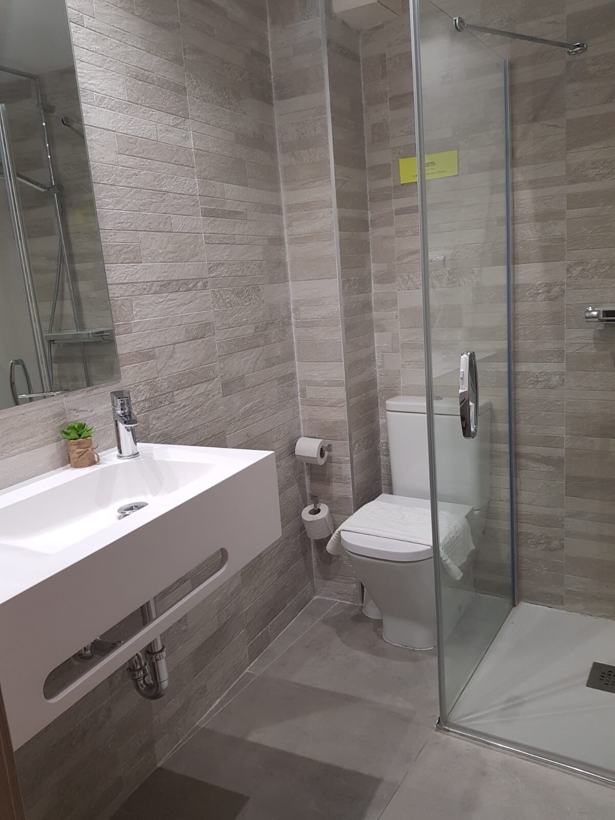 A modern bathroom with a glass shower enclosure, a white sink, and a toilet.