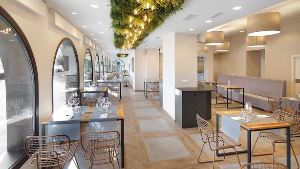 A modern restaurant interior with wooden flooring, metal chairs, and tables set for dining. - Hotel El Cobertizo (La Sotonera)