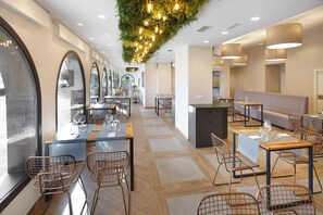 A modern restaurant interior with wooden flooring, metal chairs, and tables set for dining. - Hotel El Cobertizo (La Sotonera)