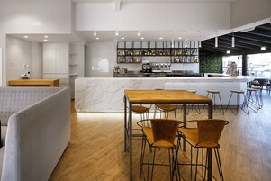 Zona de bar moderna con encimera de mármol, taburetes de madera y una variedad de botellas de licor.