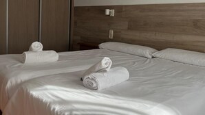 A hotel room with a large bed, two pillows, and two rolled towels on the bed. - Hotel El Cobertizo (La Sotonera)