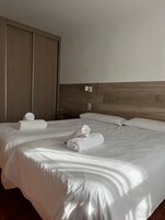 Habitación de hotel con una cama grande, dos almohadas y dos toallas enrolladas sobre la cama.