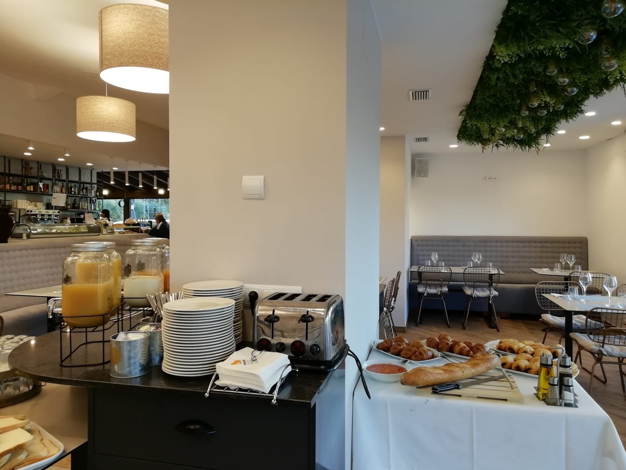 A breakfast buffet setup with various food items, a toaster, and a juice dispenser.