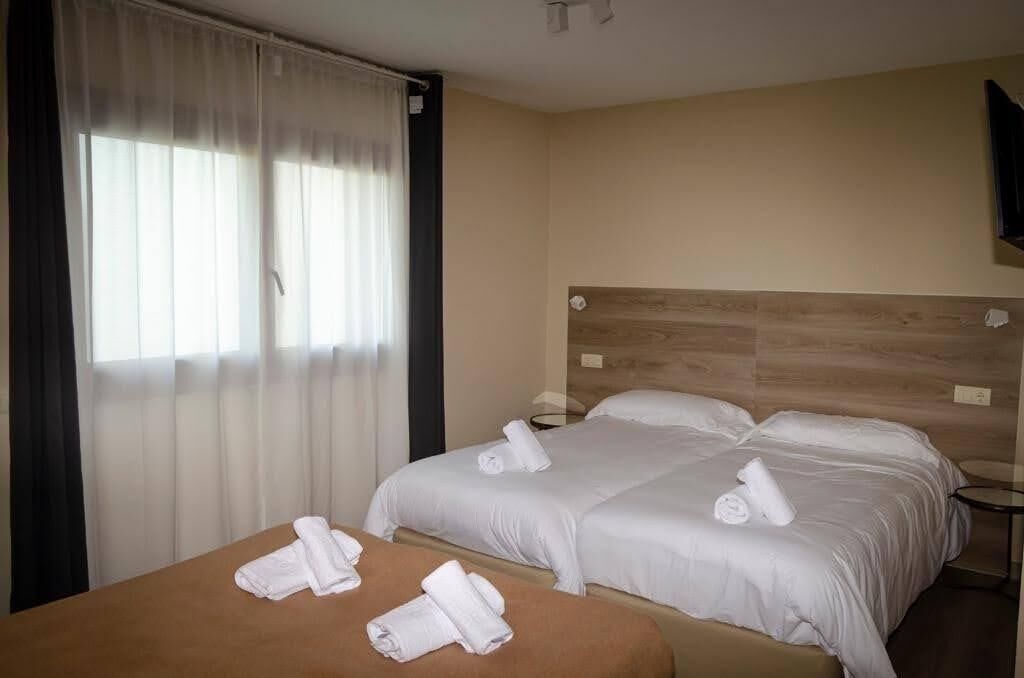 Une chambre d’hôtel avec deux lits, une tête de lit en bois et une petite table.