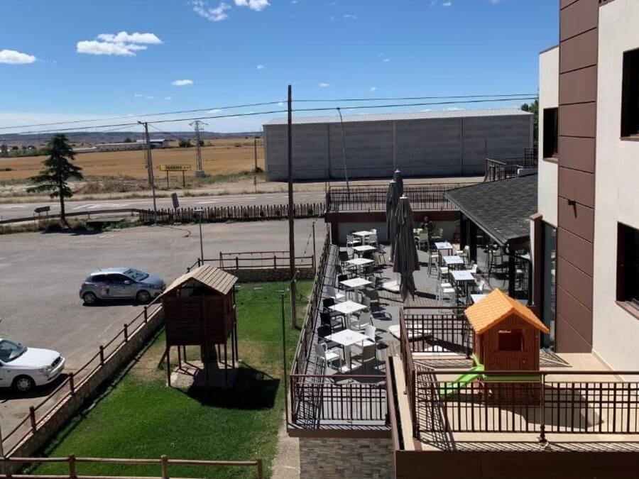 A patio area with outdoor seating, a small playhouse, and a fenced parking lot.