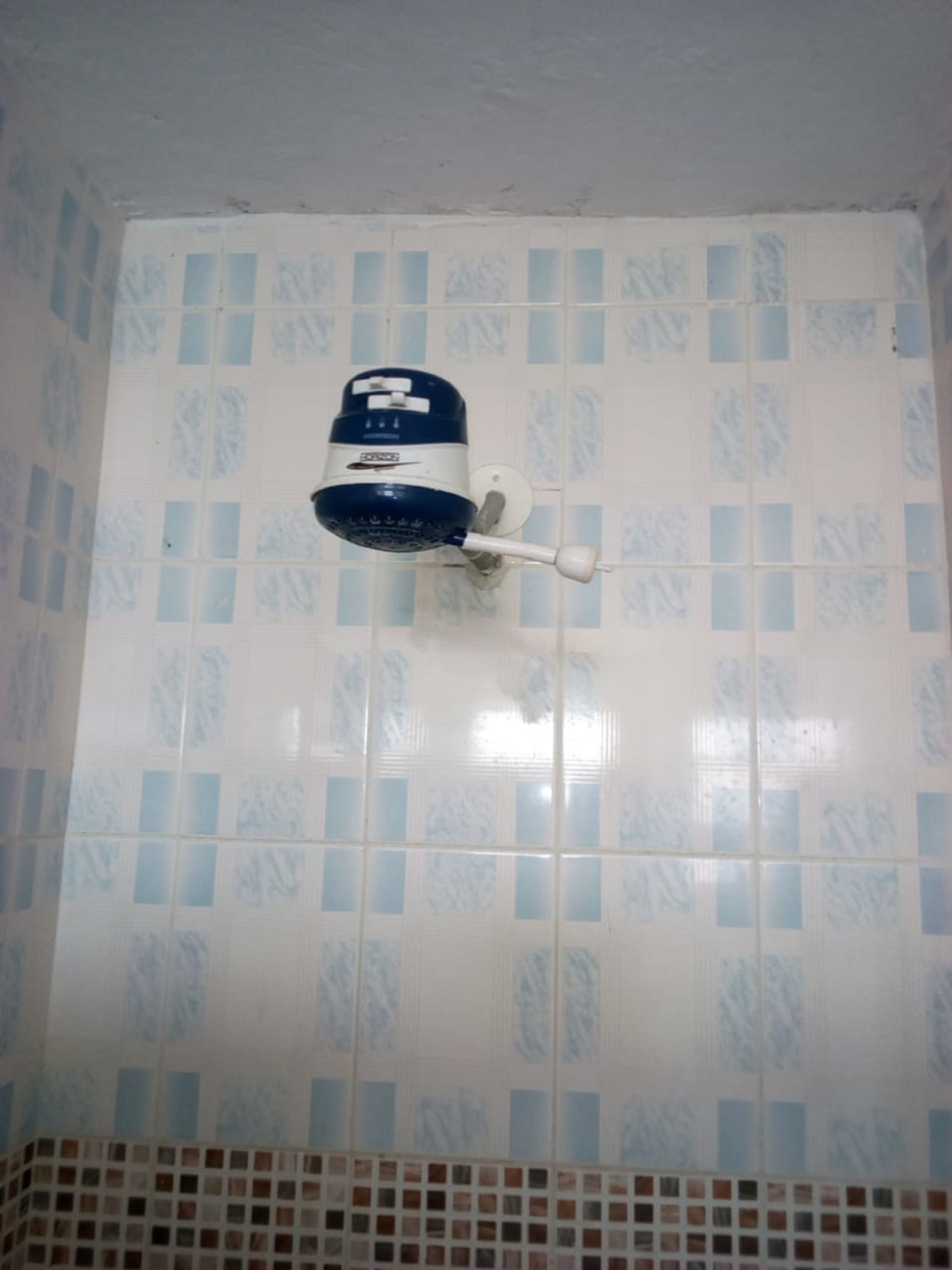 A bathroom with a wall-mounted hairdryer and a tiled wall with a pattern.