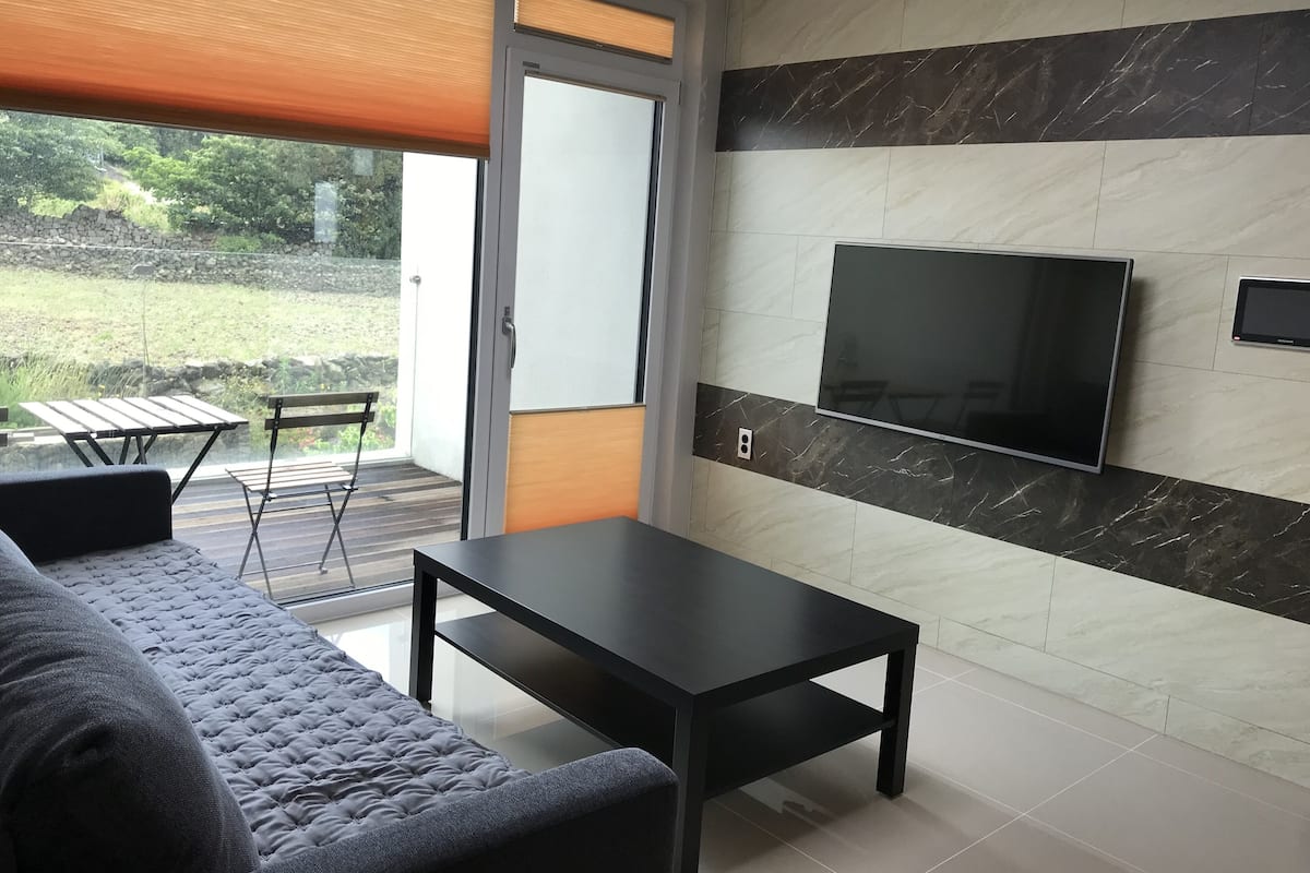 A modern living room with a sofa, a coffee table, and a TV mounted on the wall.