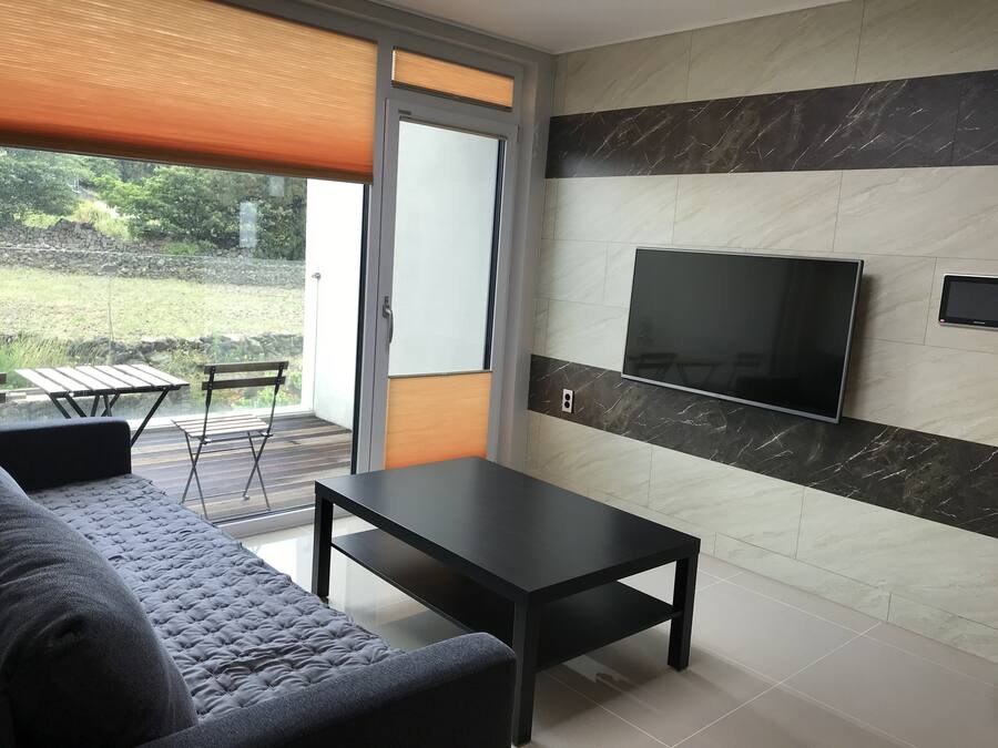 A modern living room with a sofa, a coffee table, and a TV mounted on the wall.