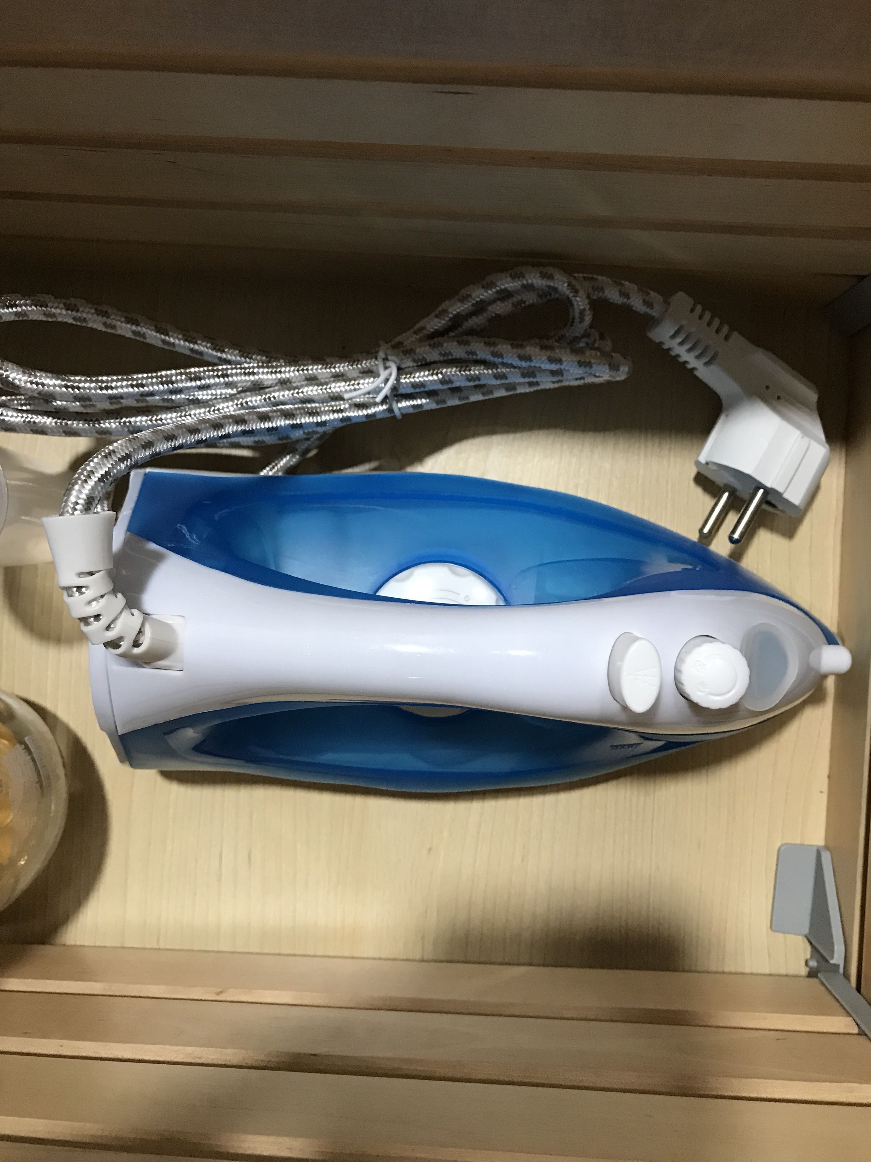 Un cepillo eléctrico azul y blanco con cable, sobre una superficie de madera.