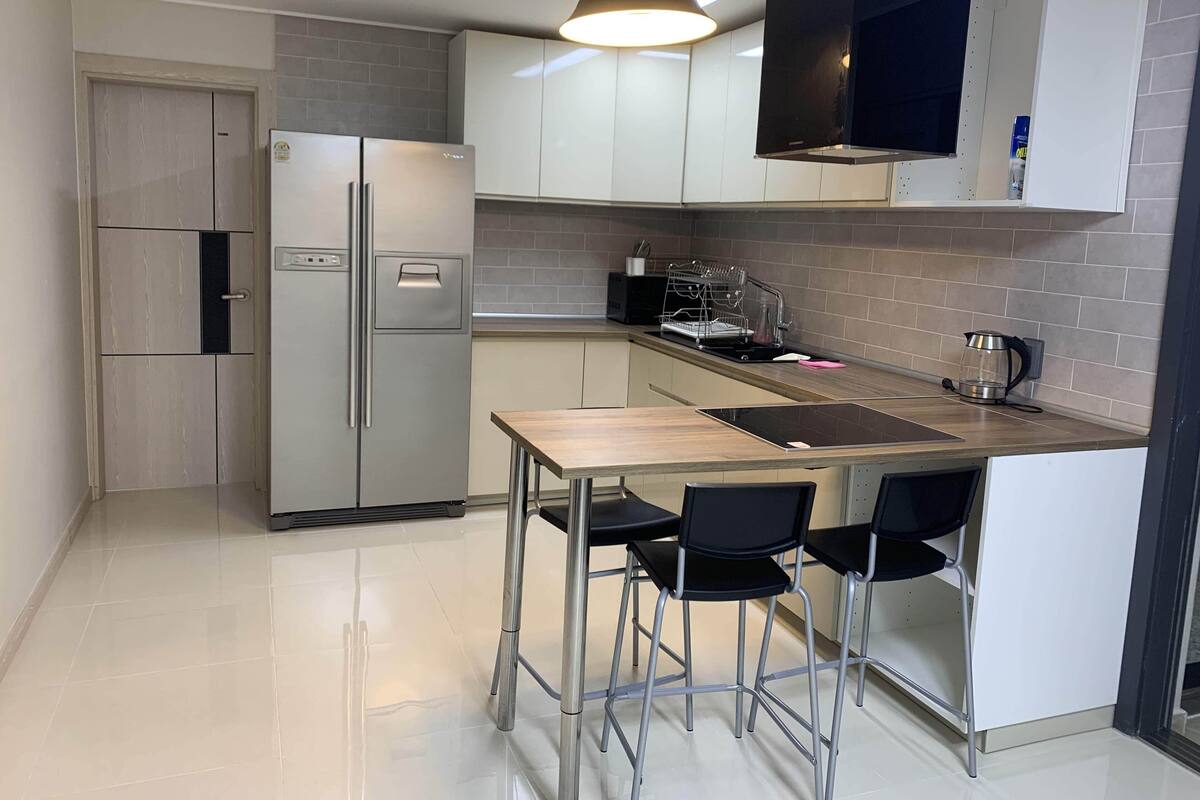 A compact kitchen with a refrigerator, a sink, a stove, and a dining area with two chairs.