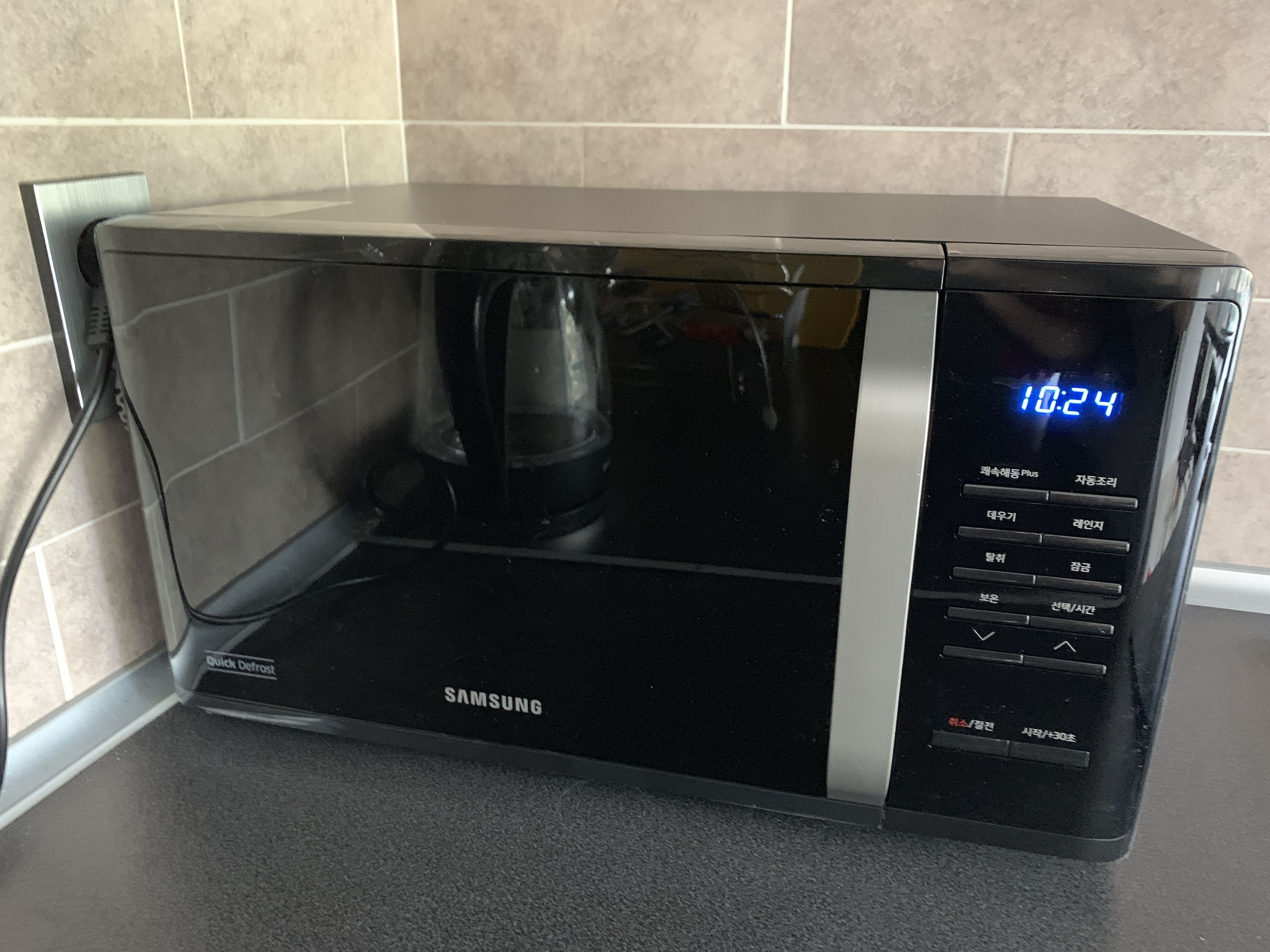 A Samsung microwave with a digital display, quick defrost feature, and multiple buttons.