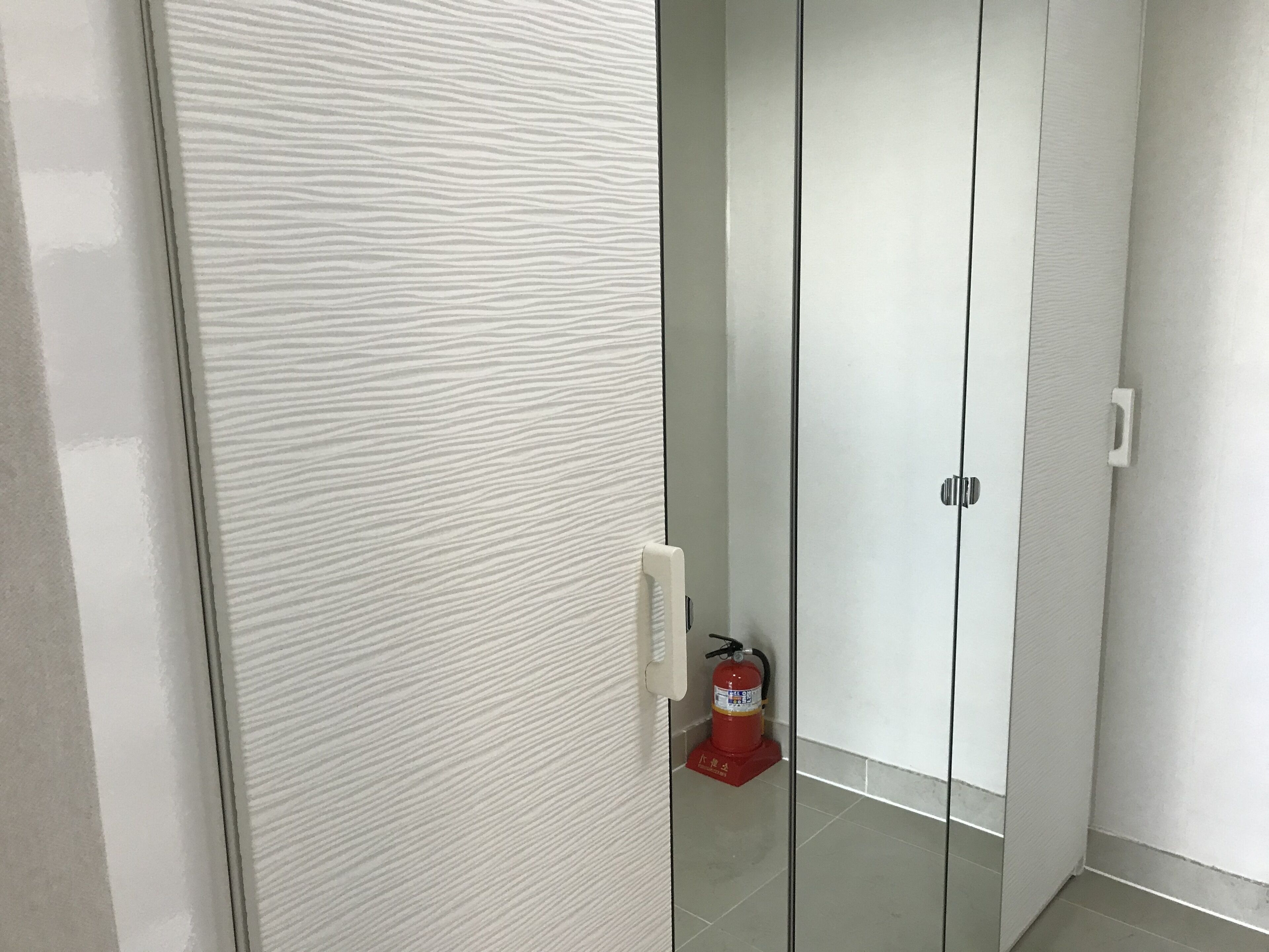 A modern room with a sliding door, a fire extinguisher, and a tiled floor.
