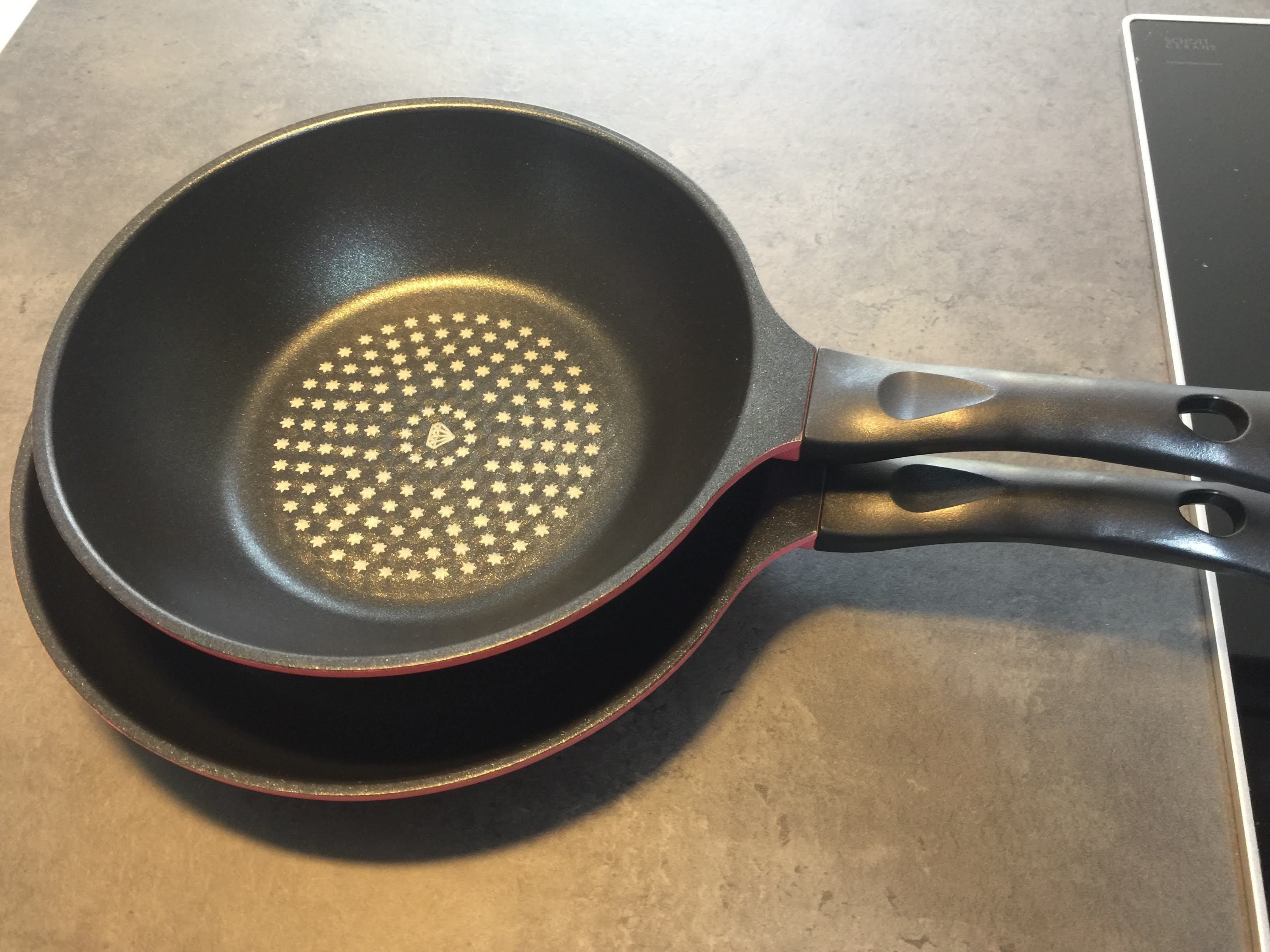 A frying pan with a non-stick surface and a red handle.