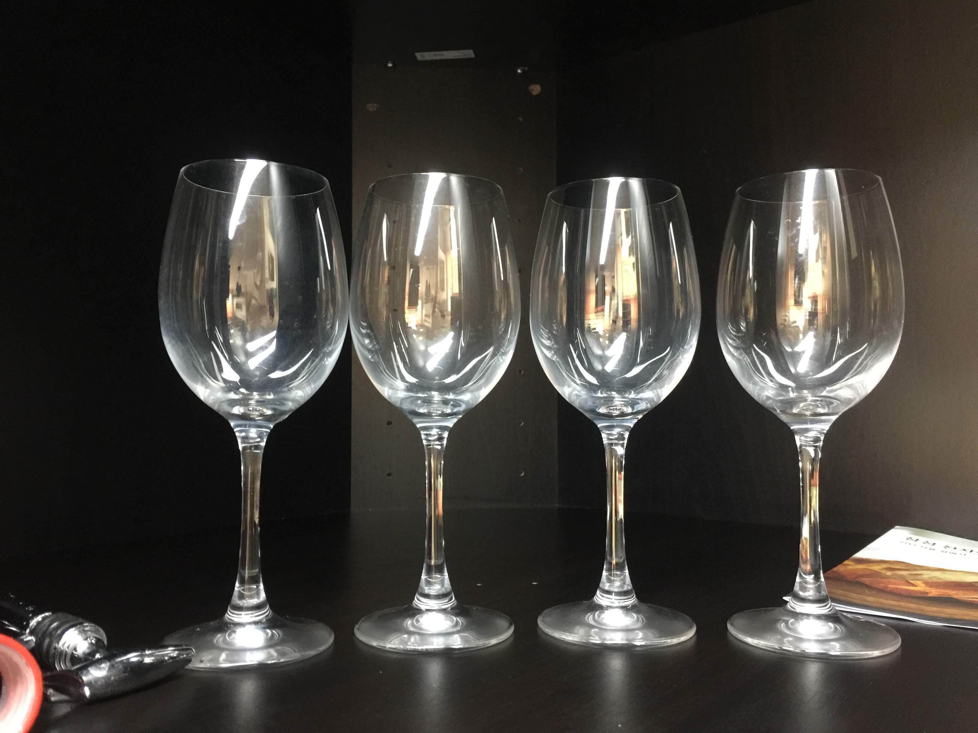 Four empty wine glasses on a dark surface with a reflective background.