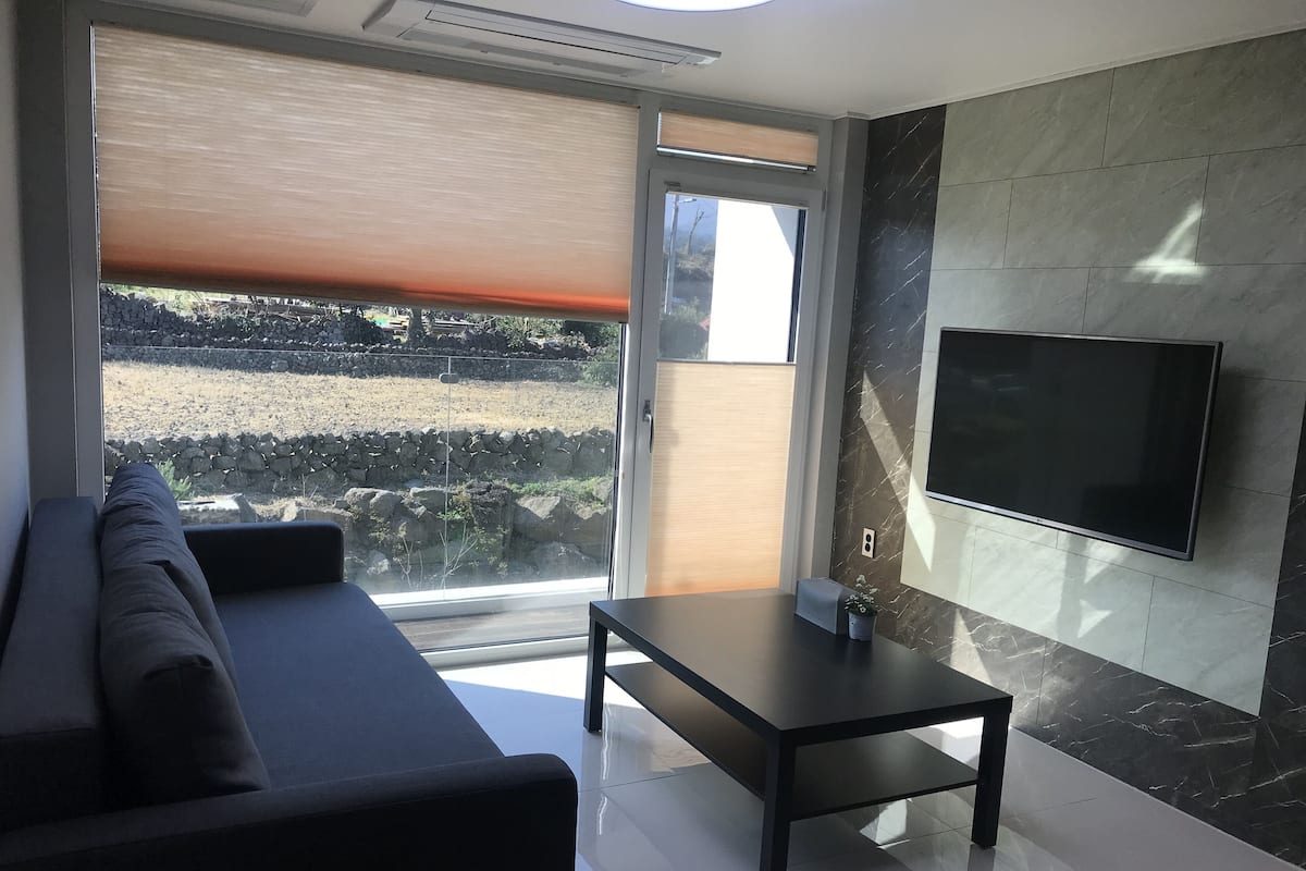 A modern living room with a sofa, a coffee table, and a TV mounted on the wall.